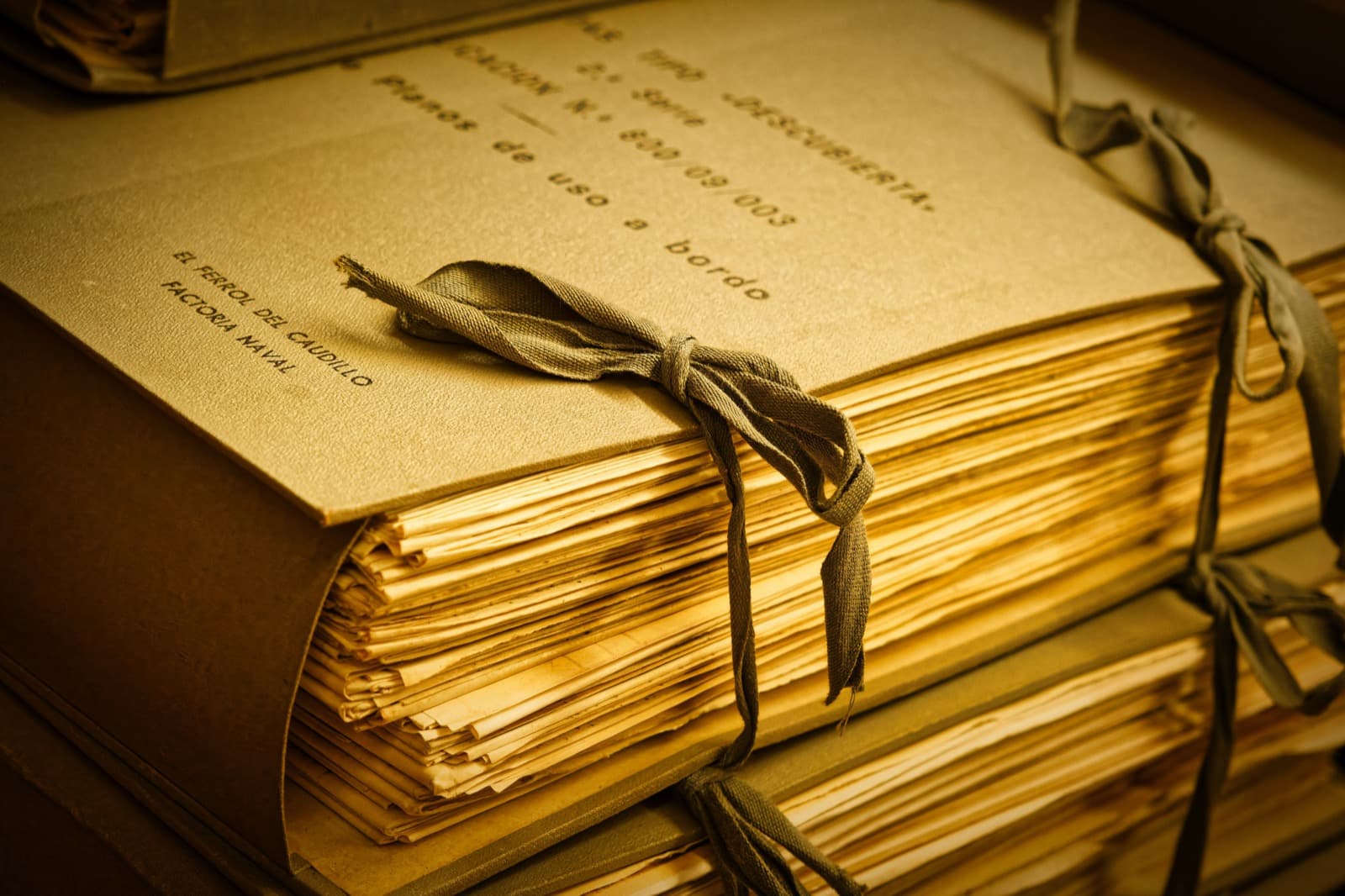 Bundles of old documents tied with ribbon on a shelf in an archive room